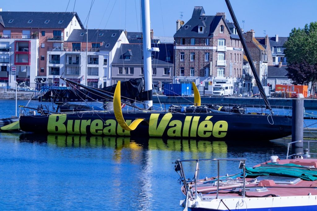 Voilier en mer avec inscription Bureau Vallée, bâtiments en arrière-plan